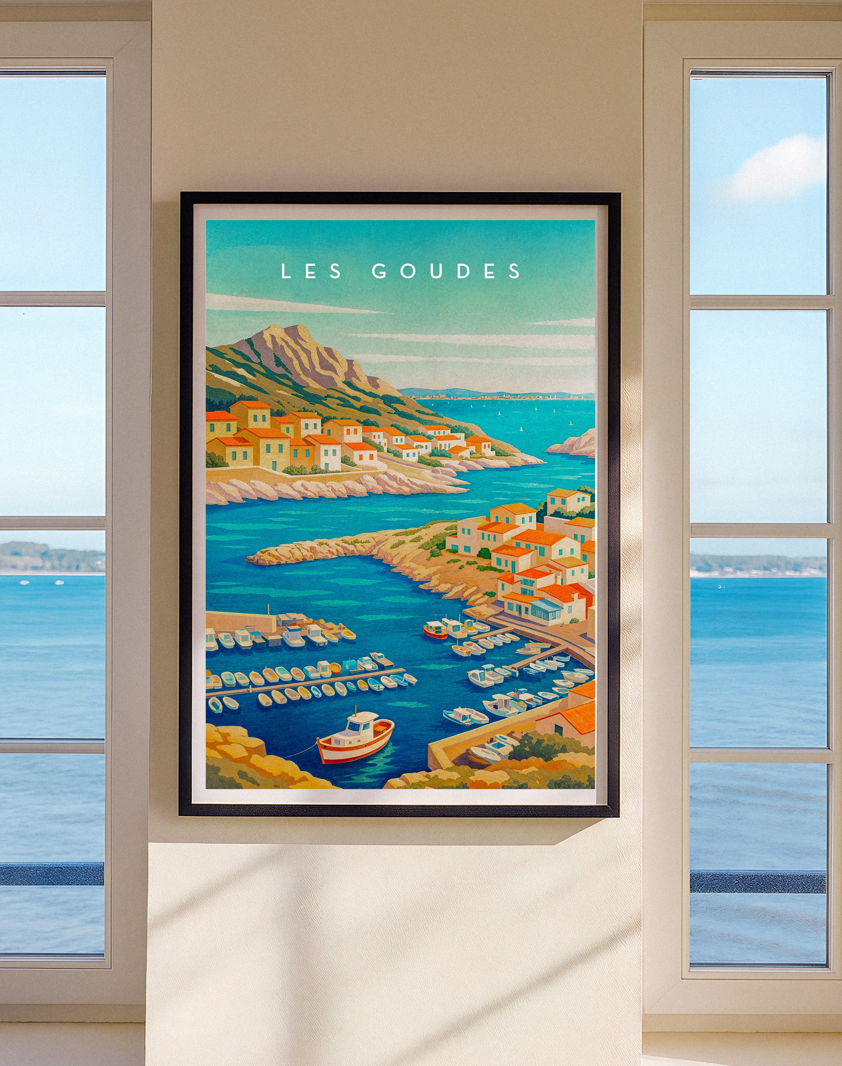 Framed artwork of Les Goudes with a coastal scene, displayed on a wall with large windows.